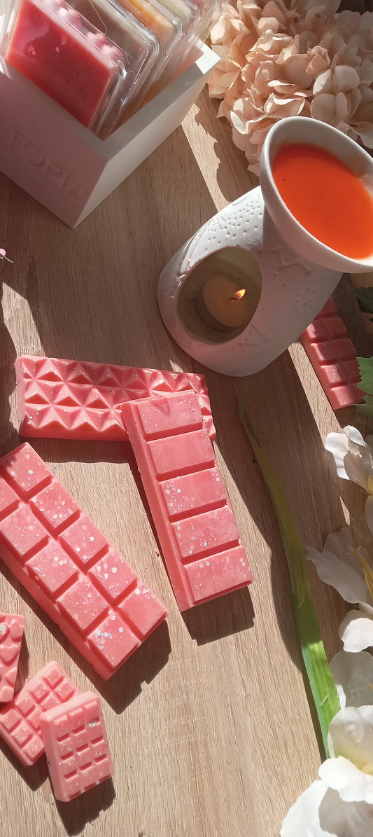 Pink wax melts on a wooden surface with a lit candle and decorative elements.