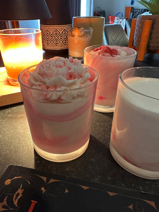 three pink and white Yuzu & Dragonfruit scented coconut wax wickless candles with pink and white coconut wax melts on the top in clear glass candle jars on a dark surface with a candle warmer lamp in the background